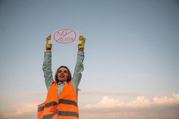 Hands holding banner with 'no plastic' text on it. Woman volunteer is against trash pollution...