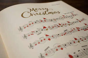 A music sheet for a Merry Christmas song, with musical notes adorned with Santa hat. Concept on the...