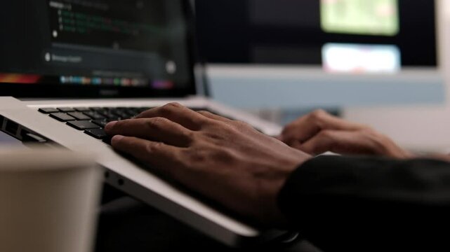 Stylish male employee in black shirt working online on computer in office. Close up on hands of a manager typing texts on a keyboard and using mouse. scrolling the trackpad.