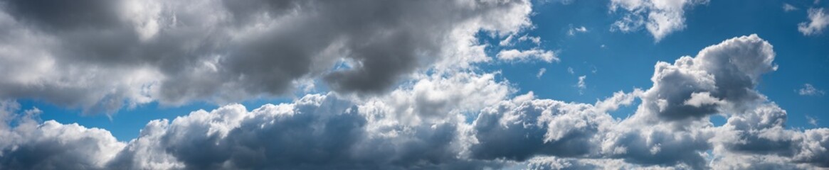 Obraz premium big sky panorama, cumulus clouds with brightly seam, against blue background
