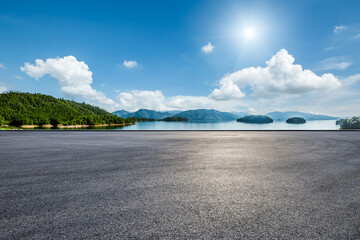 Asphalt road square and clear lake with green mountain nature landscape under blue sky. Car background.