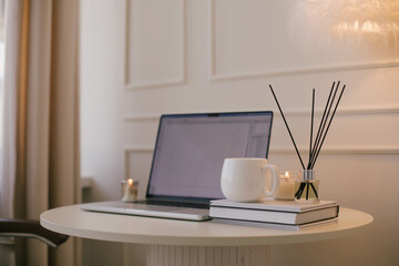 Laptop and white mug with tea on a table. Workspace in a modern room.