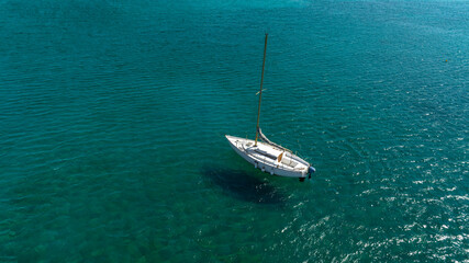 Fototapeta premium Aerial view of a lonely white sailboat in the sea. Boat holidays concept.