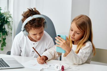 Boy and girl studying together at home, engrossed in their online learning The siblings are sitting...