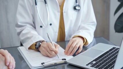 Doctor completing paperwork with patient. Close-up of a doctor's hands with forms, imparting...