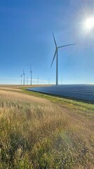 Obraz premium Wind turbines and solar panels harmonize under a clear blue sky in a rural landscape