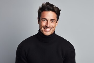 Obraz premium Portrait of a smiling man in his 30s wearing a classic turtleneck sweater while standing against white background