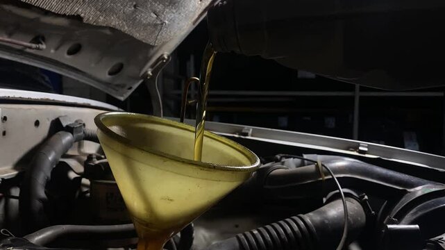 The mechanic poured new oil into the engine. Maintaining the car engine.Change the engine oil and fluid system in your car