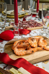 Mesa con comida para celebrar la Navidad, en primer plano tabla de madera con gambas.
