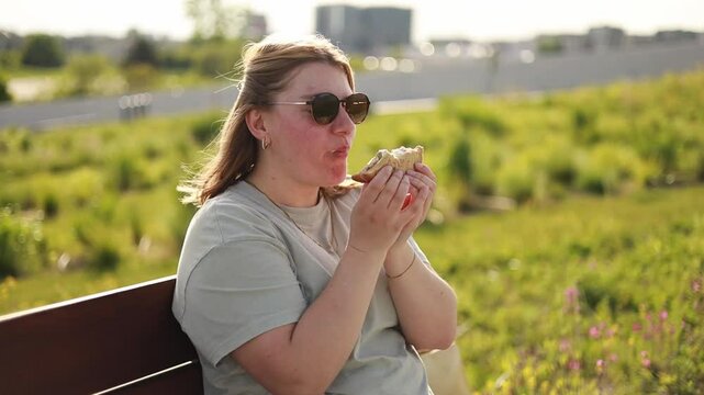 White woman eating sandwich on sunset, golden hour, epic summer scene, picnic, sun glasses on face, enjoyed woman's face, summer vibes, sunset in park, peaceful outdoor meal, overweight, chubby woman