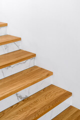 Wooden stairs featuring marble treads against copy space white wall