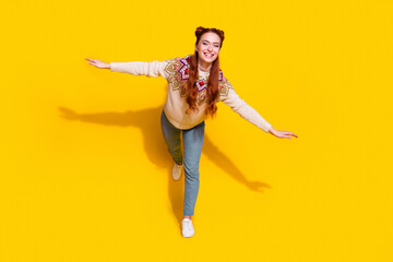 Photo portrait of attractive young woman spread hands flying dressed stylish knitted warm outfit isolated on yellow color background