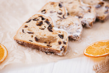 Christmas stollen on wooden background. Traditional christmas german dessert cut into pieces. Cake with nuts, raisins with marzipan and dried fruit on cutting board. baking for xmas