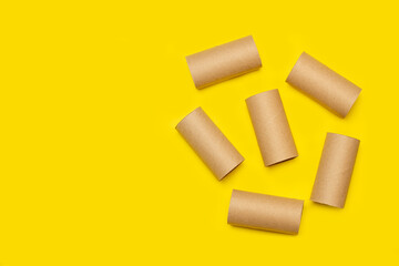 Cardboard toilet paper rolls without paper on a yellow background with copy space