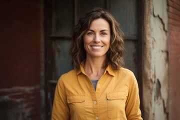 Fototapeta premium Portrait of a grinning woman in her 40s sporting a breathable hiking shirt over vintage brick wall