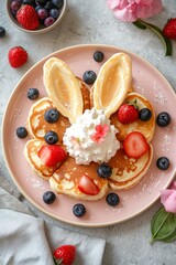 Obraz premium Overhead shot of fluffy pancakes shaped like bunny ears, with a delicate dollop of whipped cream and fresh berries, on a light rose plate