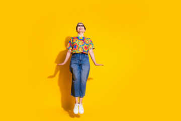 Full body portrait of nice aged lady jump look empty space wear t-shirt isolated on yellow color background