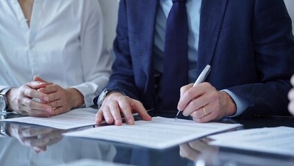 Business people wearing suits signing important documents during a corporate meeting. Win-win...