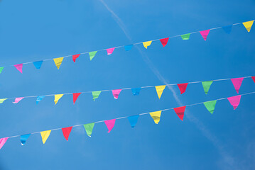 colorful triangular flags on three lines, blue sky background