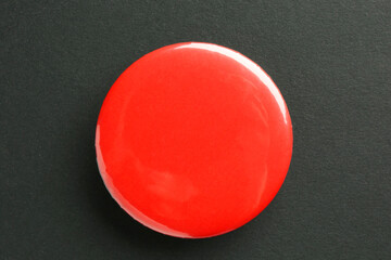 Red button badge on black background, top view. Mockup for design