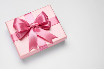 Gift box with pink bow on light grey background, top view. Space for text