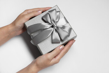 Woman holding gift box with bow on white background, closeup