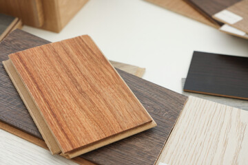 Different samples of wooden flooring on white table, closeup