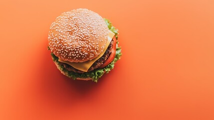 Top-down view of a classic cheeseburger with sesame bun on vibrant orange background, featuring fresh ingredients and melted cheese.