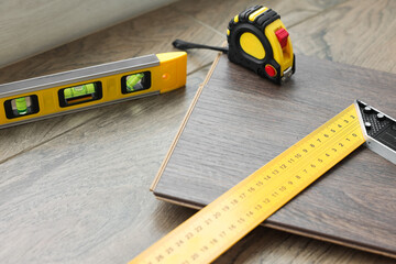 Measuring tools and laminate flooring pieces on wooden surface, closeup