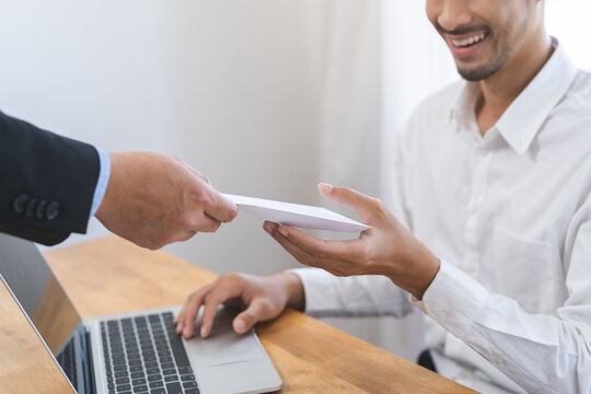 Good job Asian manager business man giving financial reward in an envelope, business letter extra salary to company employee, male worker office hand received premium bonus, getting cheque from boss.