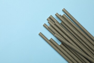 Bamboo drinking straws on light blue background, top view. Space for text