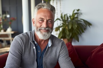 Fototapeta premium Portrait of a satisfied man in his 60s wearing a chic cardigan isolated in modern minimalist interior