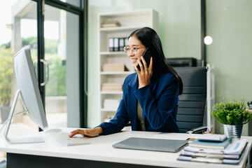 Asian woman sitting at a desk using a laptop computer Navigating Finance and Marketing