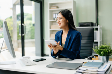 Asian woman sitting at a desk using a laptop computer Navigating Finance and Marketing