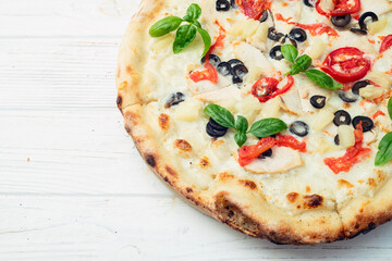 Pizza with mozzarella cheese , olives , chicken , pineapple , basil and tomatoes