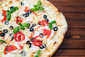 Pizza with mozzarella cheese , olives , chicken , pineapple , basil and tomatoes