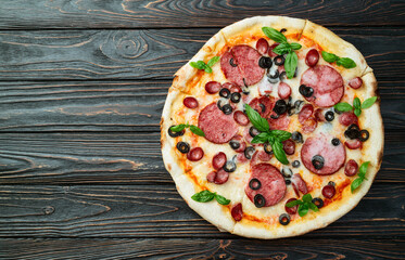 Pizza with mozzarella cheese , salami sausages , olives , and basil