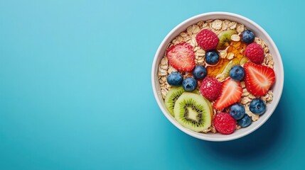 A bowl of oatmeal with berries, kiwi, and honey on a blue background.