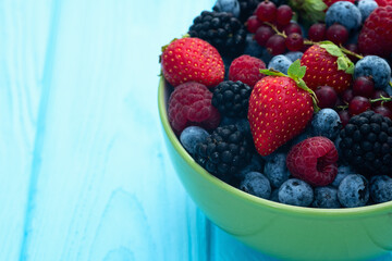 Mix of ripe colorful berries in bowl photography . Blueberry , strawberry , raspberry , blackberry and red currant . Top view