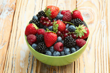 Mix of ripe colorful berries in bowl photography . Blueberry , strawberry , raspberry , blackberry and red currant . Top view