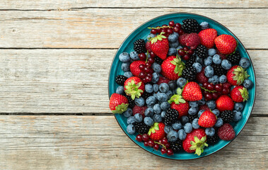 Mix of ripe colorful berries in bowl photography . Blueberry , strawberry , raspberry , blackberry and red currant . Top view
