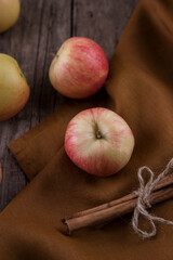 Cinnamon sticks, apples towel on wooden table