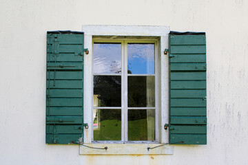 Vecchia finestra di legno ammalorata con riflessi sui vetri