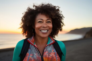 Portrait of a happy afro-american woman in her 50s wearing a lightweight running vest over beautiful beach sunset