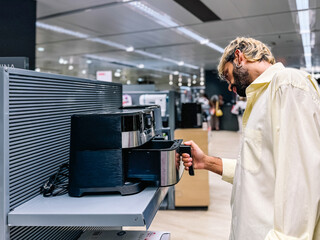 Man inspecting air fryer in an electronics store...