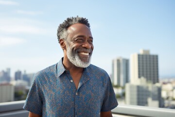 Fototapeta premium Portrait of a smiling afro-american man in his 50s donning a trendy cropped top in front of stunning skyscraper skyline