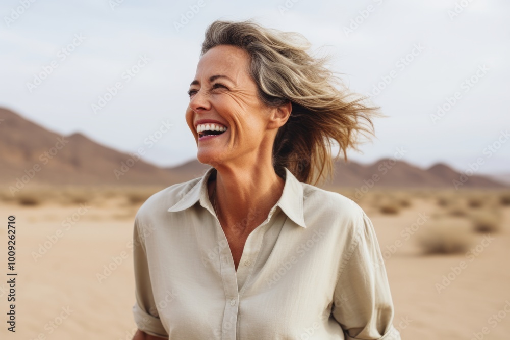 Canvas Prints Portrait of a joyful woman in her 50s wearing a simple cotton shirt while standing against backdrop of desert dunes