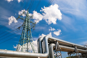 close up of pipeline and power line, blue sky and clouds in the background