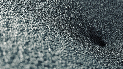Close-up view of metallic pellets forming a texture. Raw material for production of rubber products. Rubber pellets, close-up. A detailed close-up shot of small pellets, forming an abstract and