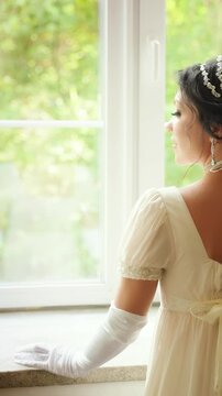Retro woman looking out window, waiting for love. Fantasy fairy sexy lady Happy Princess girl, white silk vintage long dress old style ball gown, high bun black hair hairstyle back rear view. art 4k